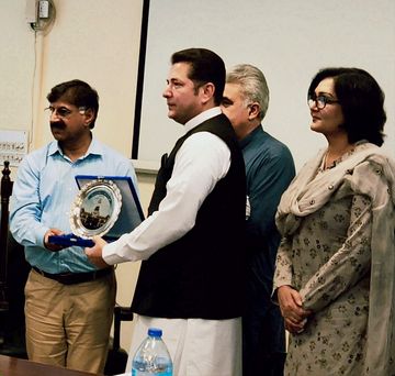 Bakhtiar Khattak receiving a commemorative shield at a ceremony